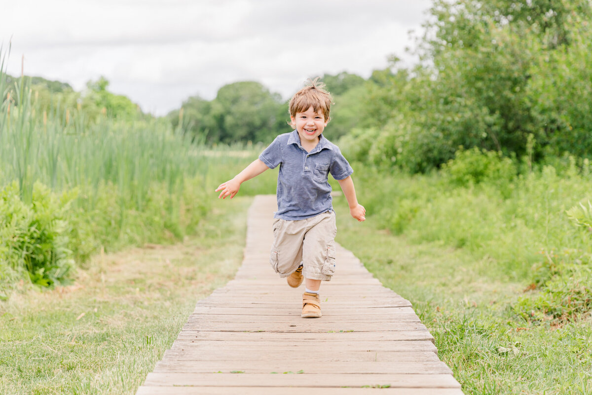 Massachusetts family photography session |  Toddler running with great joy on a wooden path surrounded by greenery