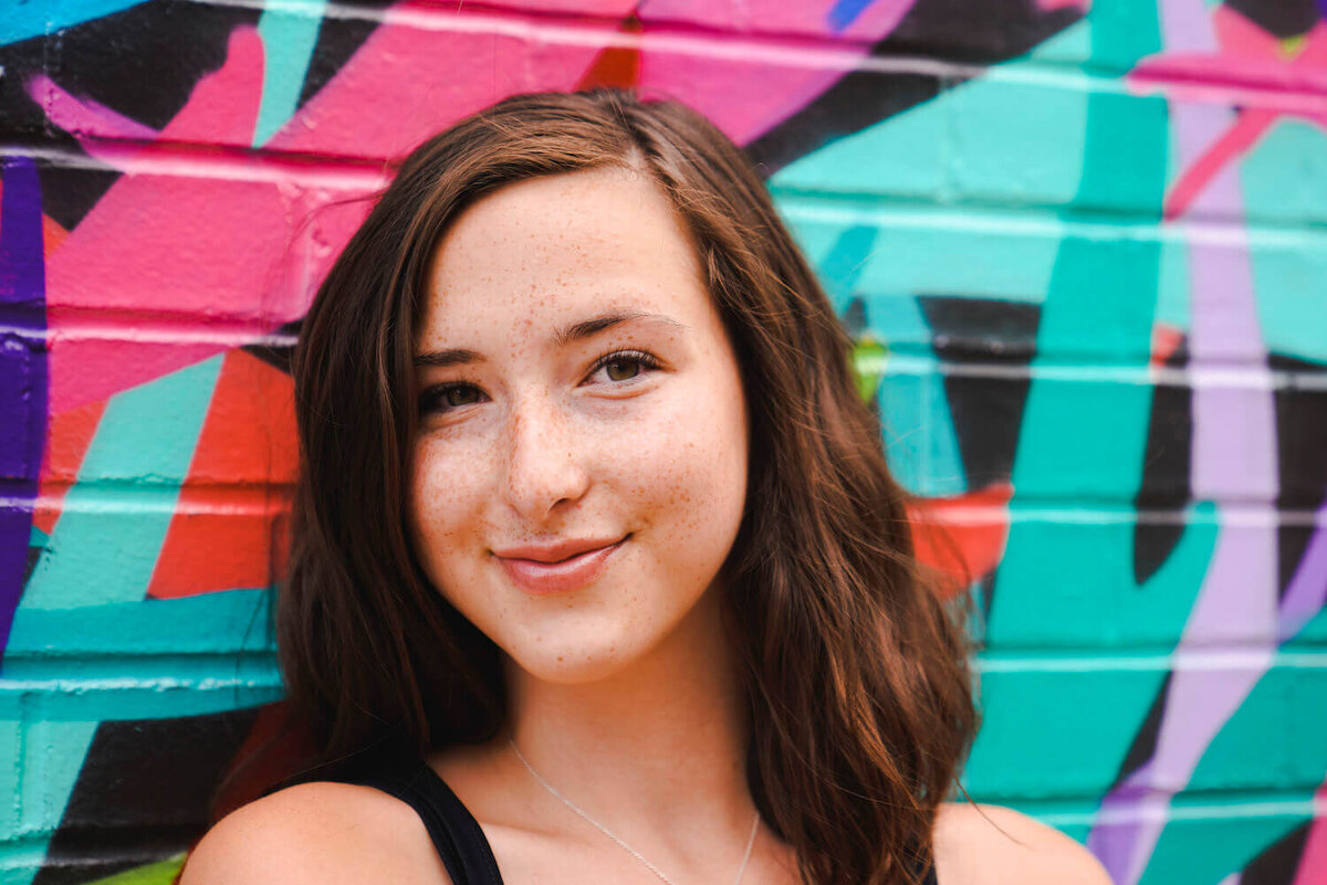 denver photographers senior pictures - girl smiling in front of bright building