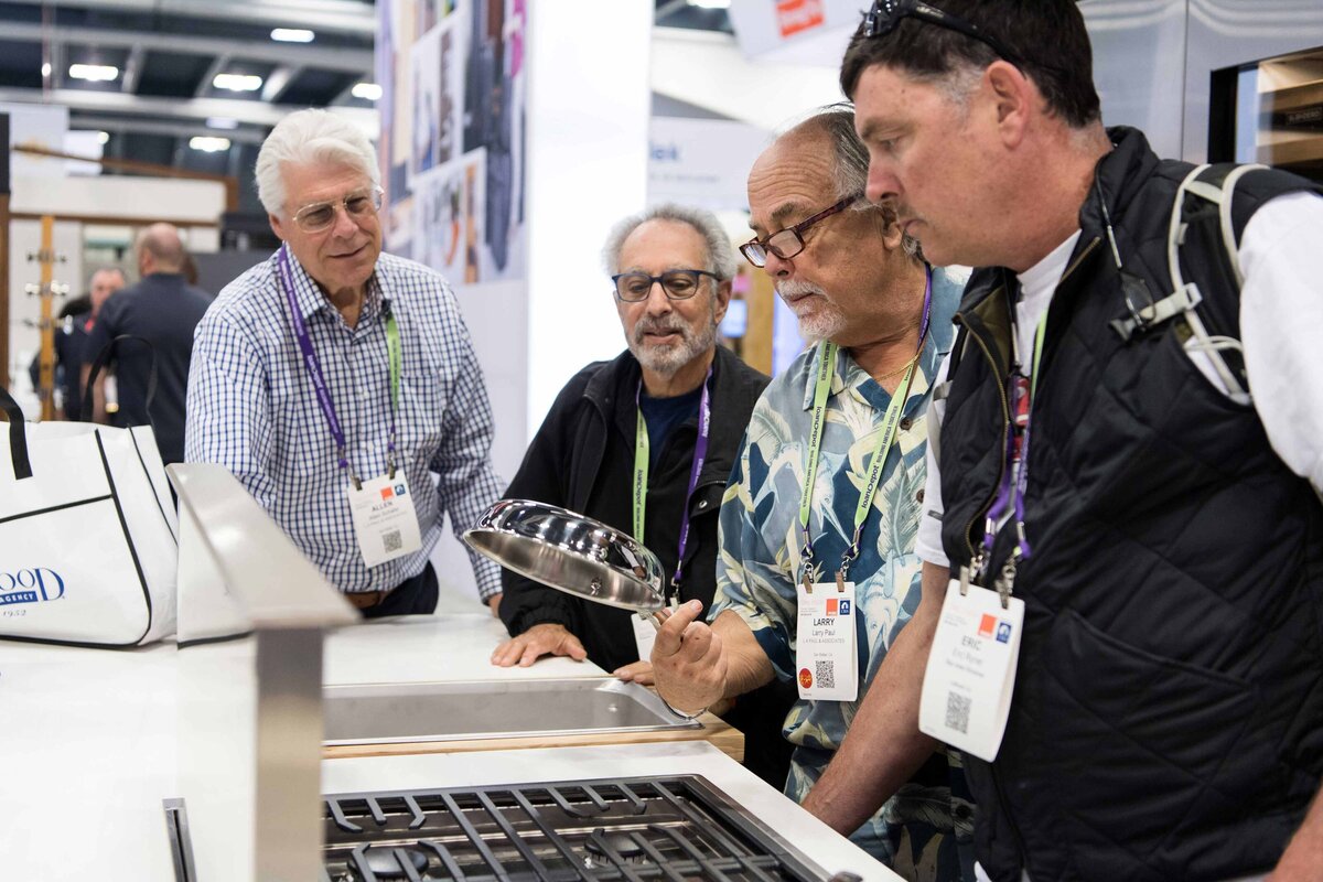 4 attendees look at the bottom of a  new chrome frying pan