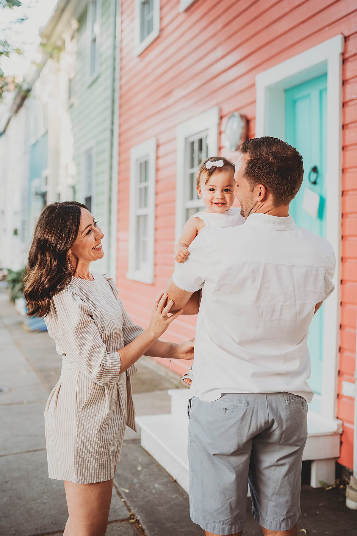 Woman and Man smiling and playing with baby in front of colorful houses in Fells Point Baltimore Maryland