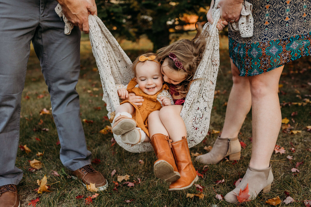 girls laughing in swing with parents fall colors