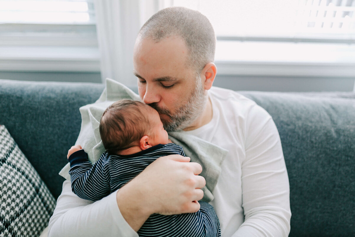 Newborn baby snuggles on the couch with Dad during his lifestyle newborn session