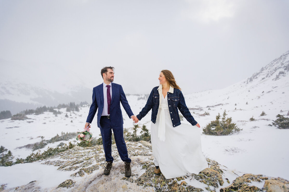 The couple holds hands looking at each other during a snow storm at Loveland Pass
