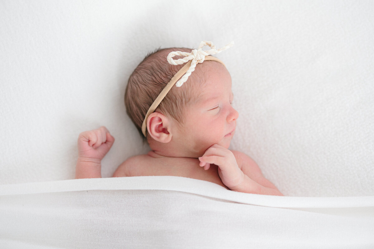 Newborn baby girl sleeping on a white backdrop during her northern kentucky newborn photography session by missy marshall