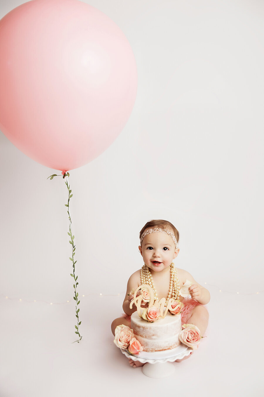 Baby girl with her birthday cake and big balloon