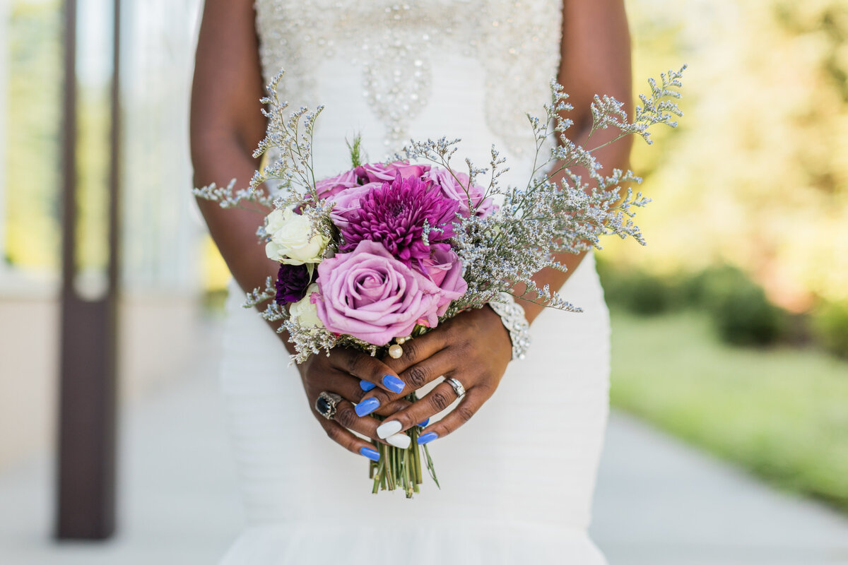 bride holding a purple flower bouquet