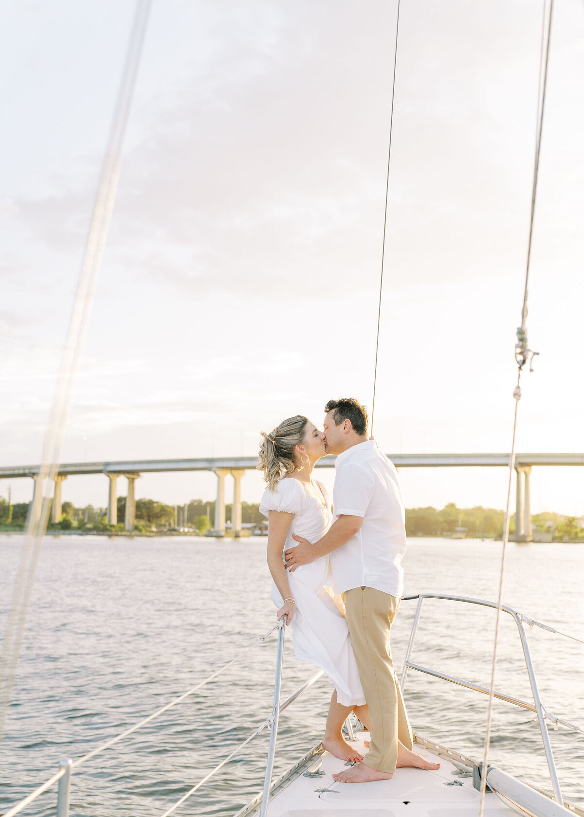 engaged couple kissing on a sailboat