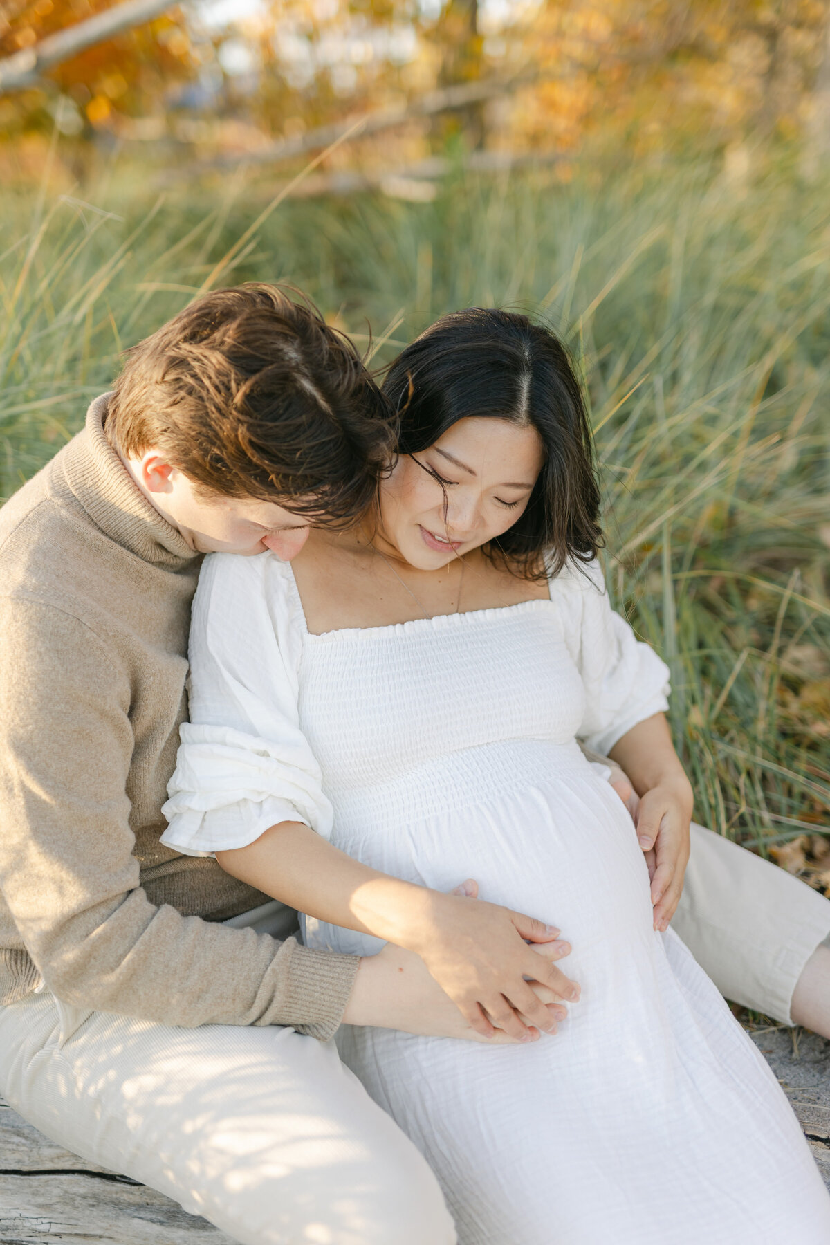 pregnant couple snuggling in the grass