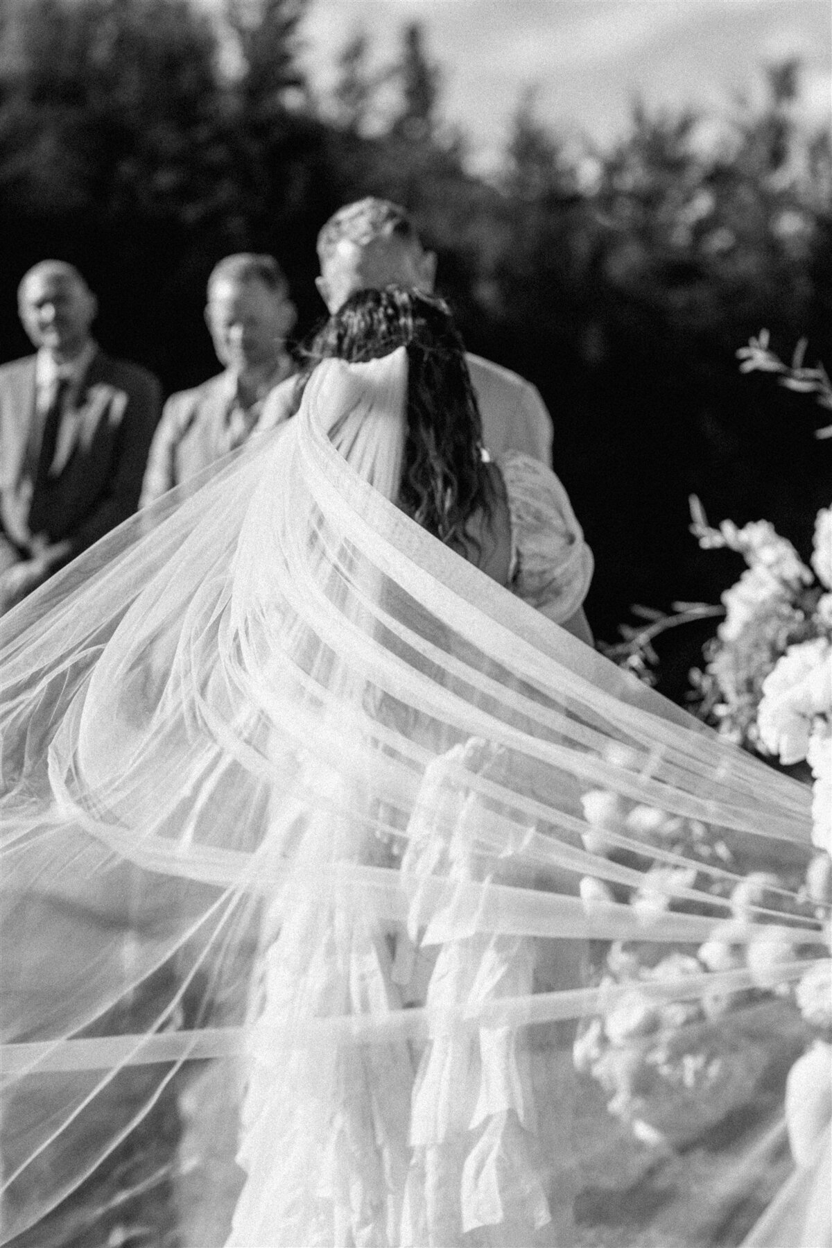 Artistic black and white photo of the bride’s long veil blowing in the wind during the Lake Hāwea wedding ceremony.