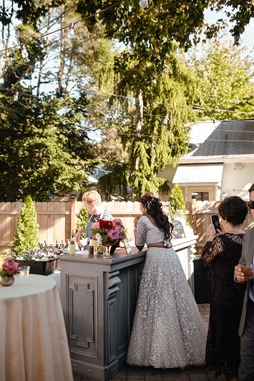 The couple standing before a floral arch, framed by a charming backyard garden and soft natural light.
