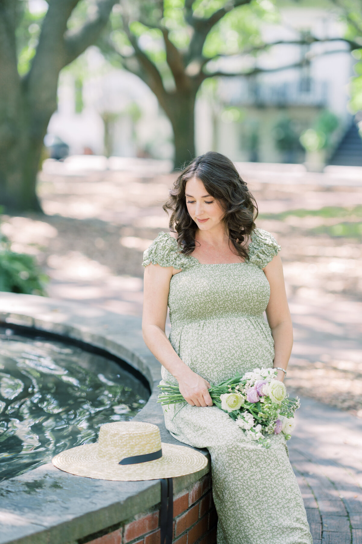 Pregnant mother sitting on rim of fountain at lafayette square by savannah family photographer courtney cronin