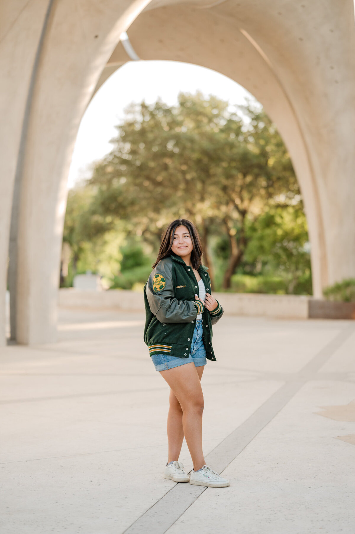Senior poses in her letterman jacket at San Antonio's Confluence Park.