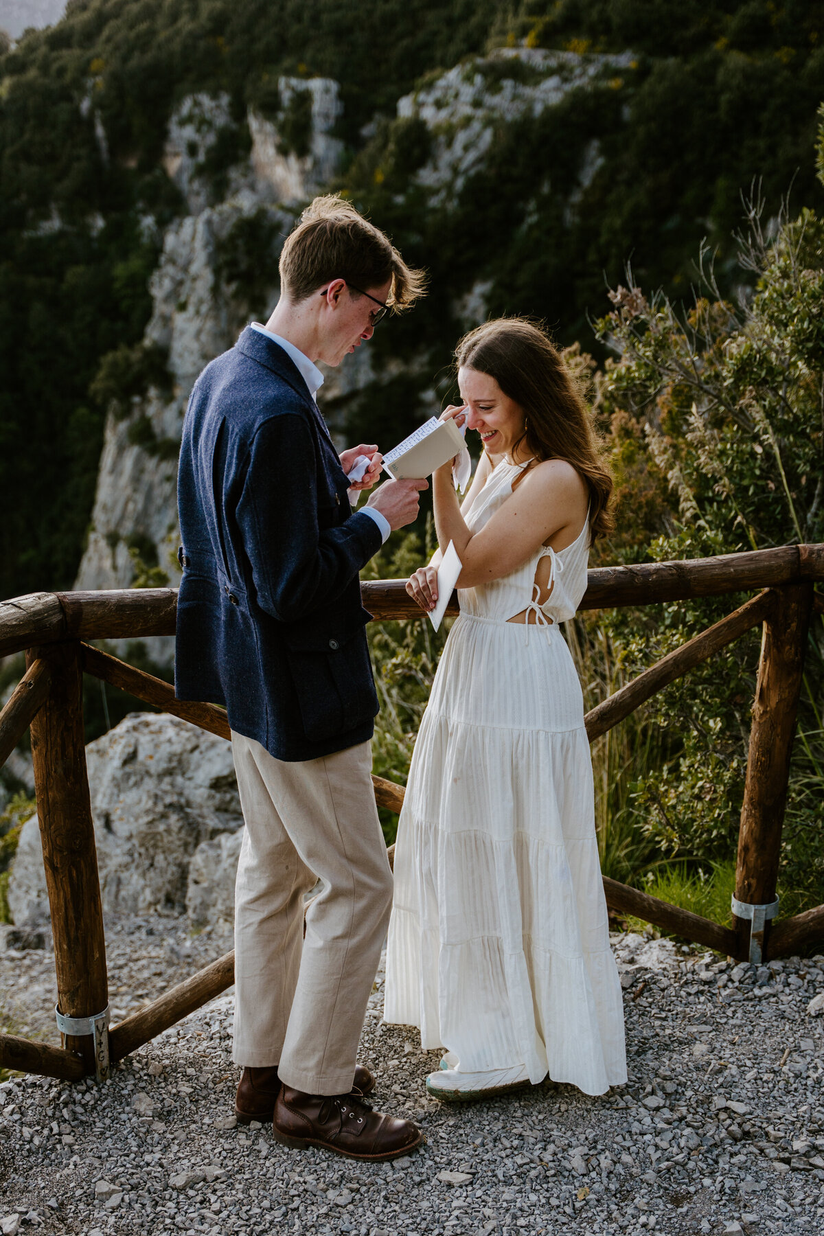 Couple reading vows at wooden railing.