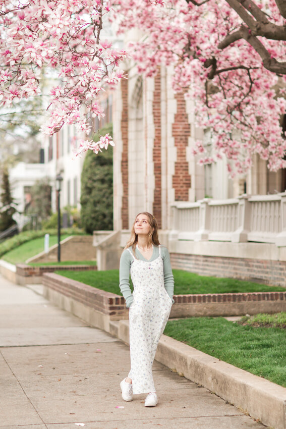 senior girl walking under pink flowers