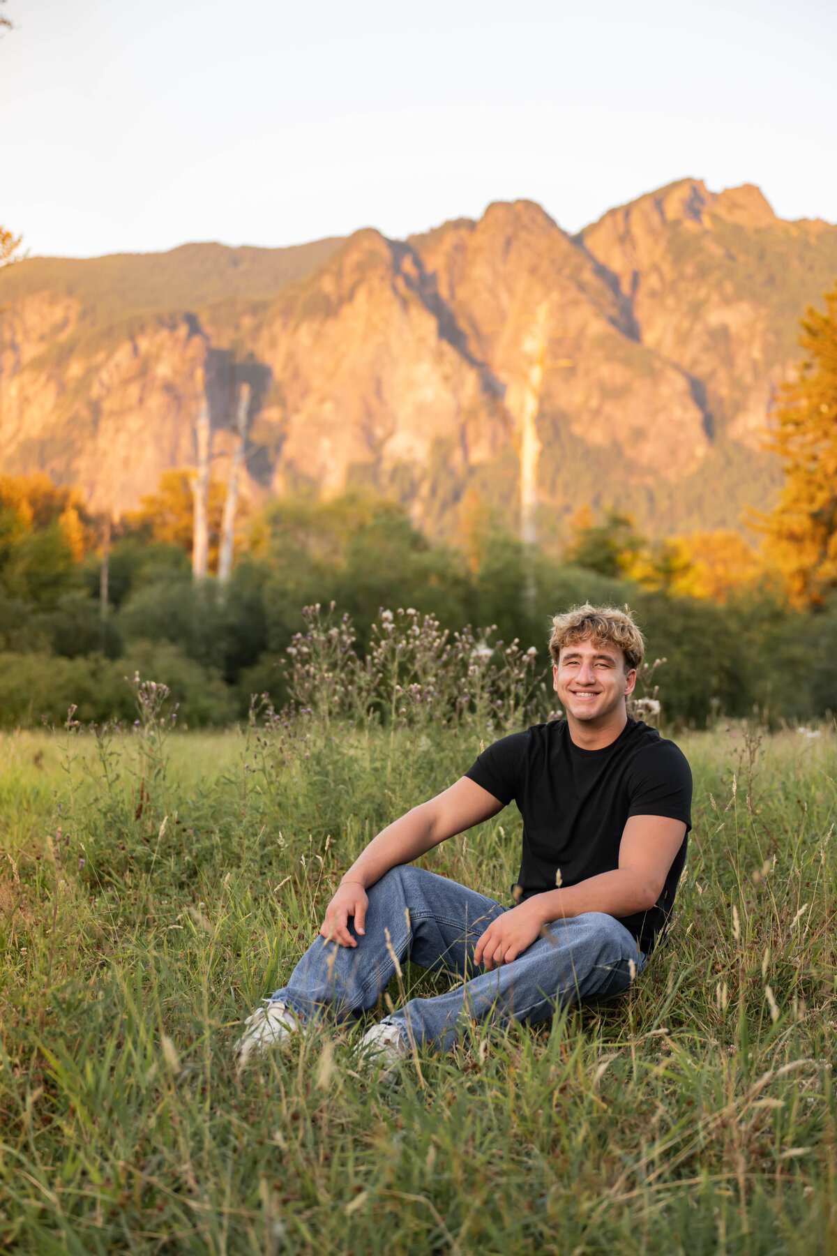 guy seated in open meadow mountains