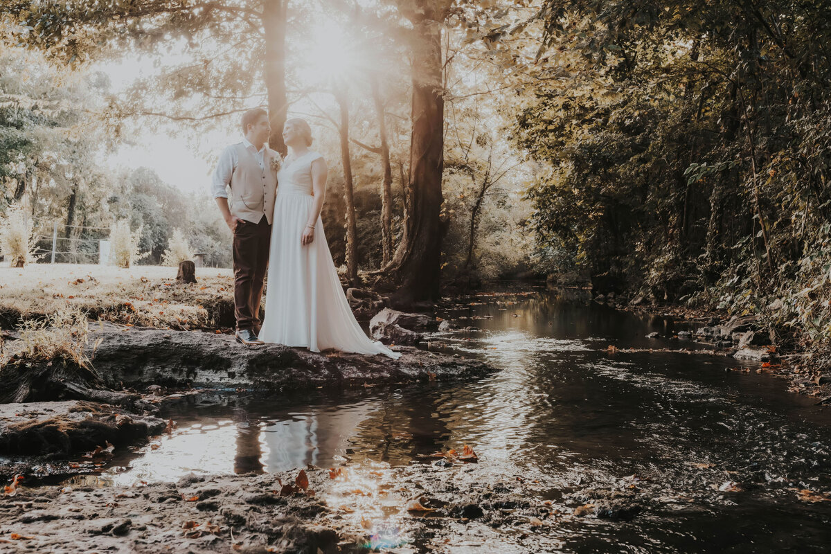 newlyweds stand near creek