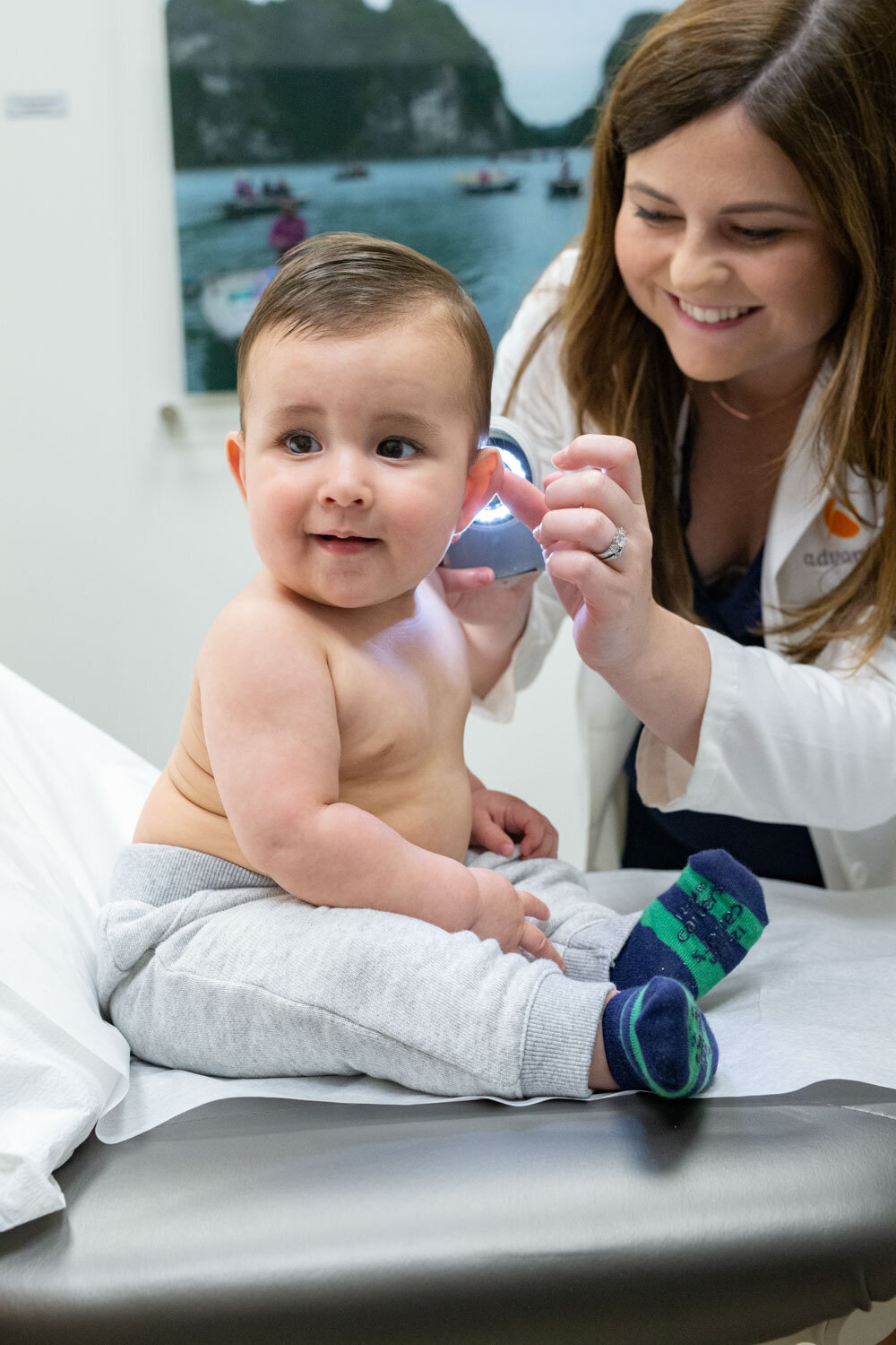 A woman is examining a baby 's ear with a light