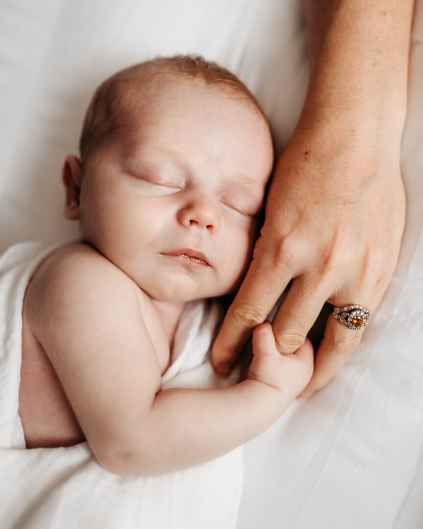 newborn baby holding mother's hand