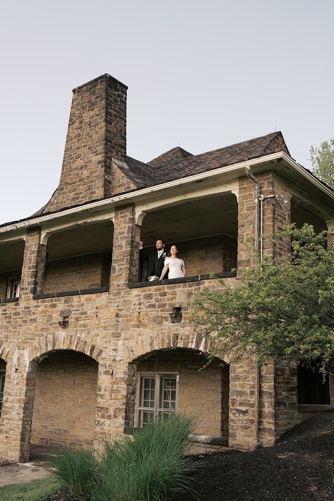 Bride and groom leaning over the railing of a stone building before their Nashville wedding reception. 