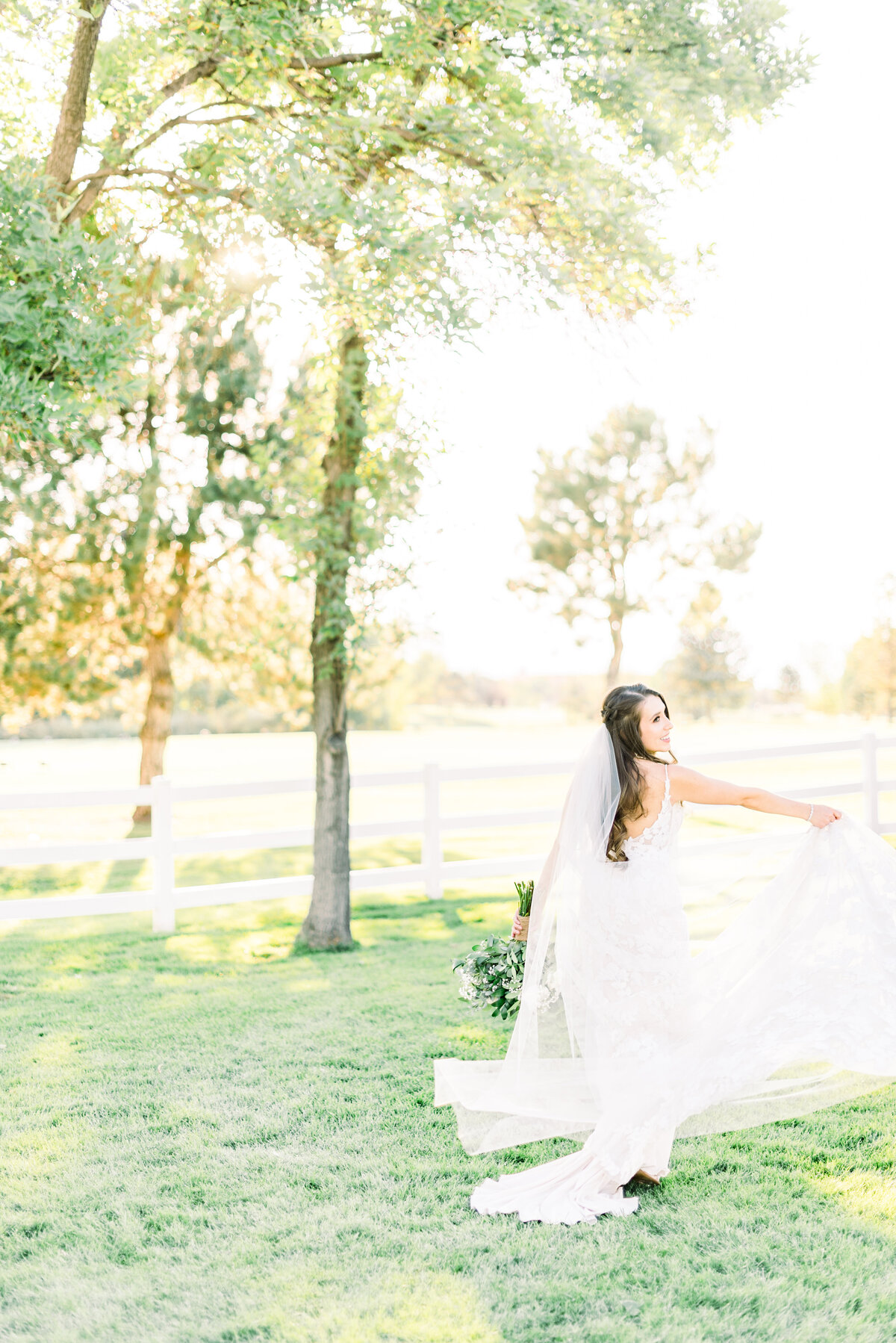 bride on her wedding day standing on a grassy lawn and spinning