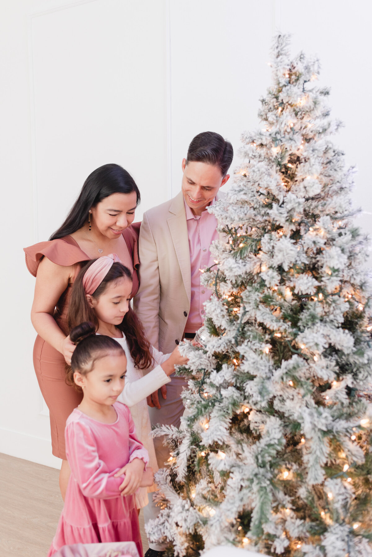 family of four putting ornaments on a christmas tree