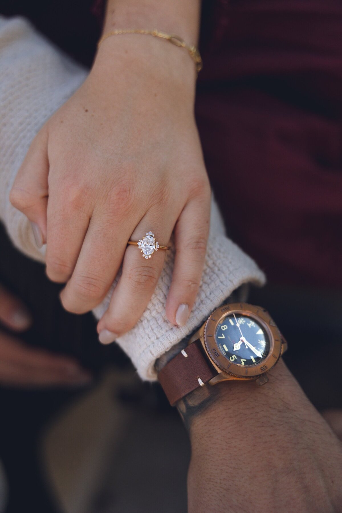 Close-up shot of couple's engagement rings and hands intertwined.