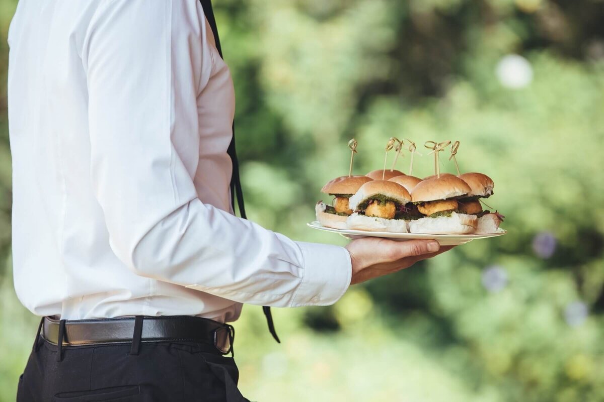 Waiter with a plate of mini sliders