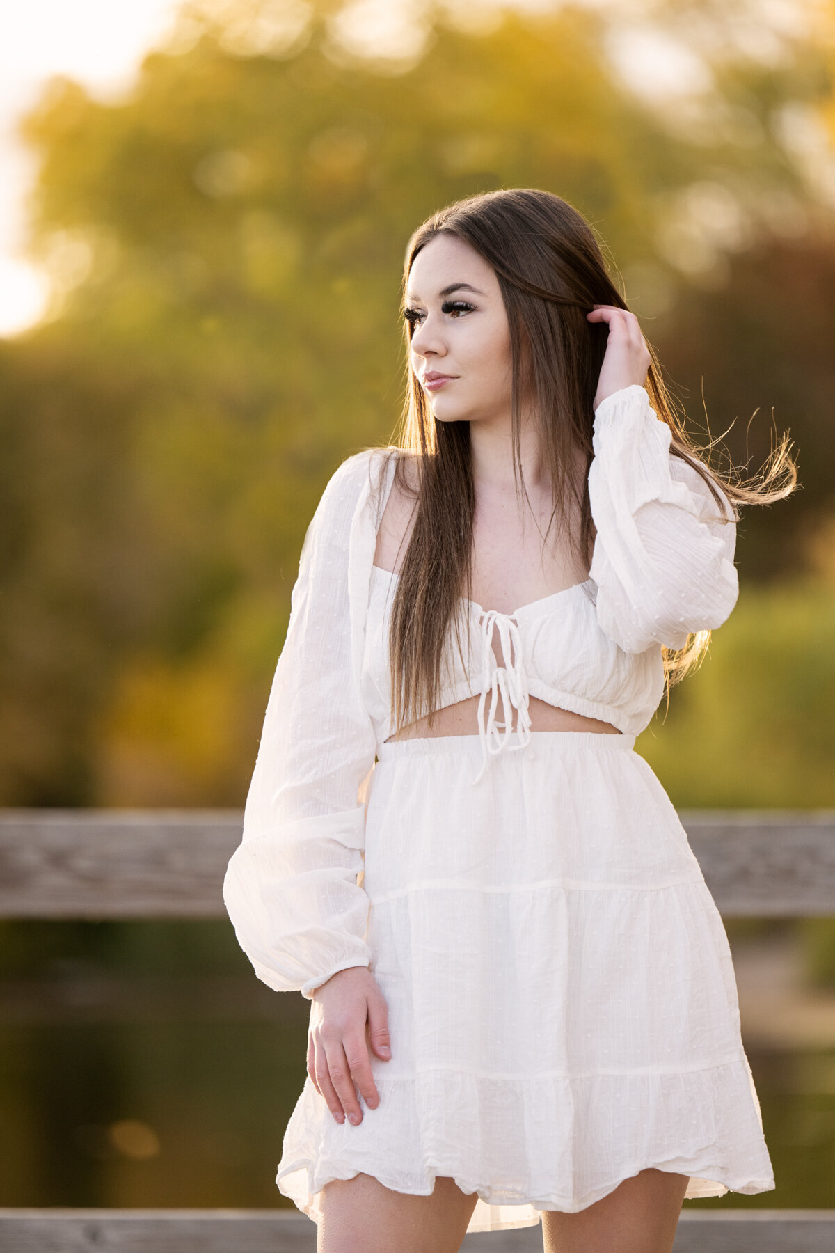 Austin Minnesota girl in white dress standing on a dock at sunset for senior pictures