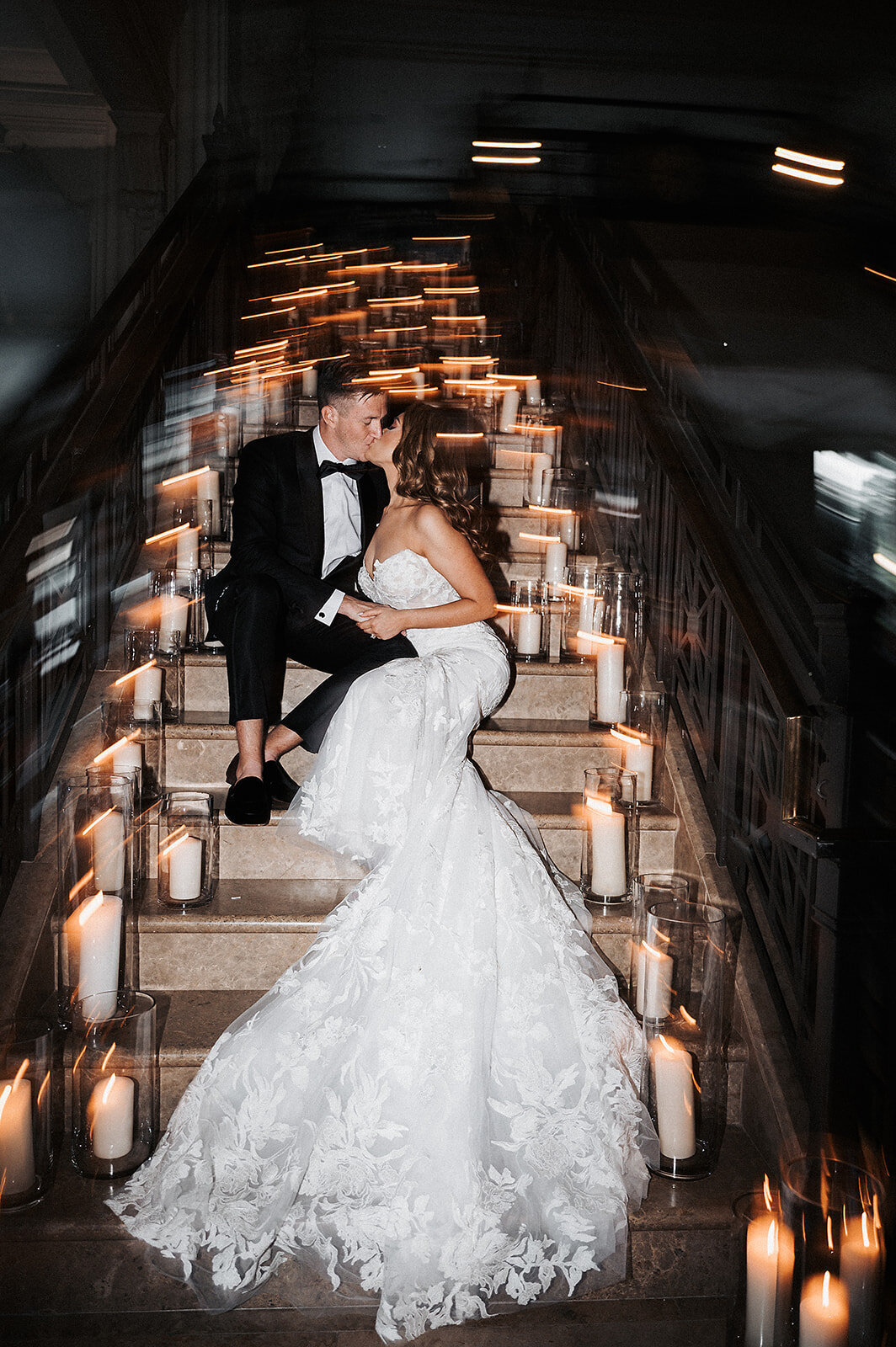 Bride and groom on stairs surrounded by candles