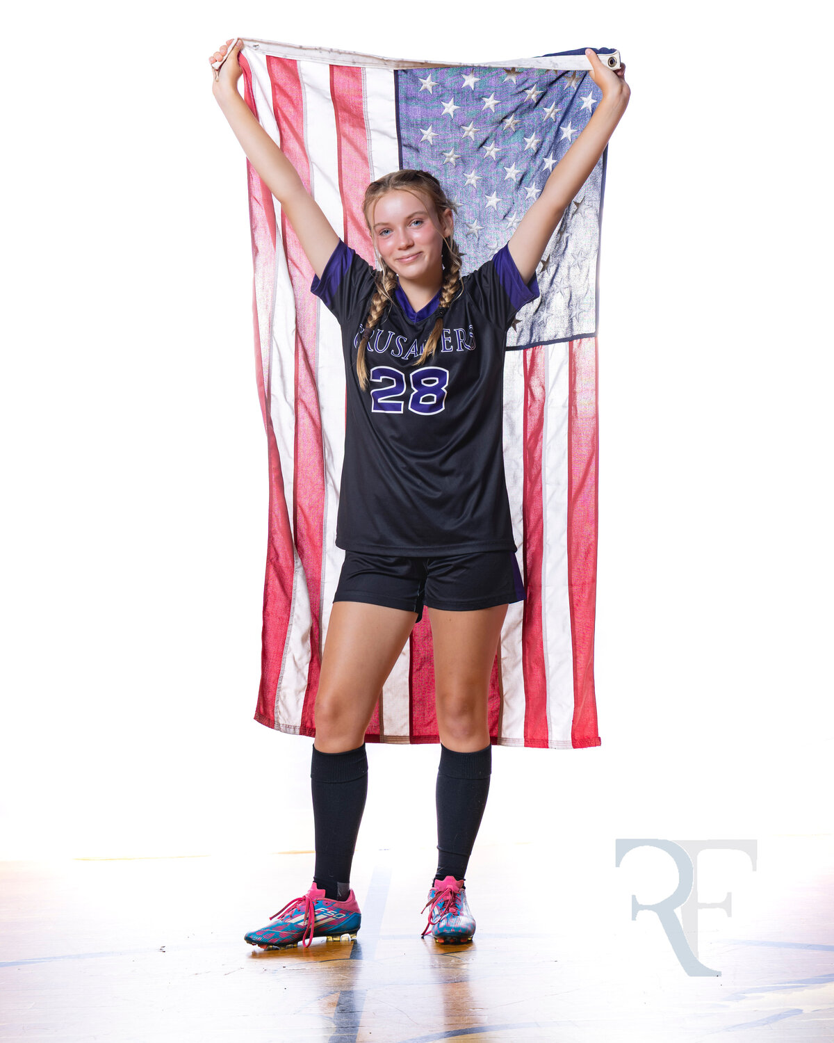 Photographer in Avon | Rob Faber Photography | Female soccer player holding an American flag behind her, wearing a Crusaders jersey and cleats.
