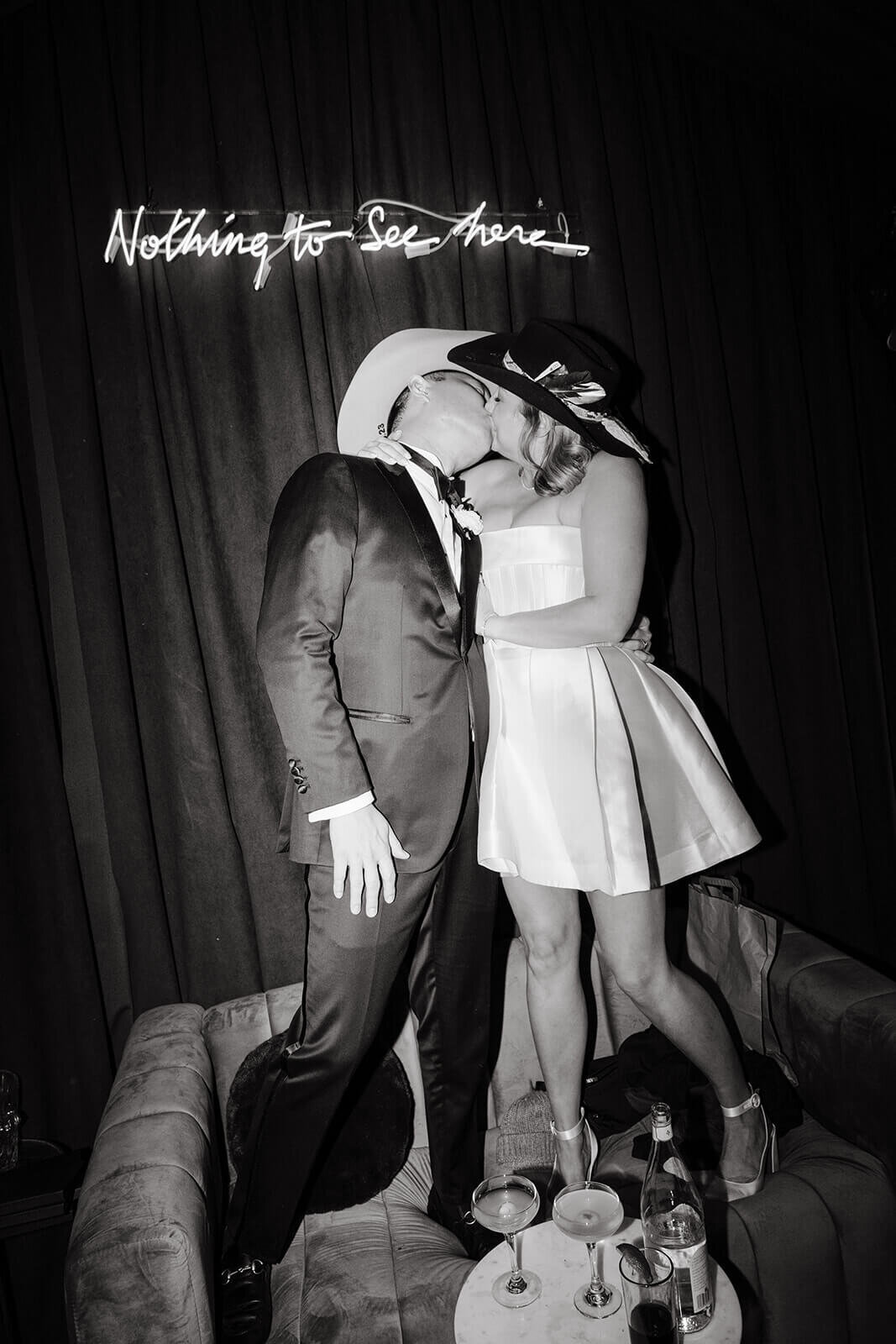 Bride and Groom sneak a kiss in the intimate wedding reception lounge area that features a neon sign at the St. Regis Aspen wedding reception.