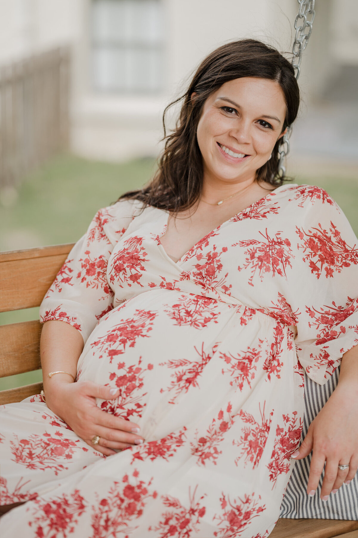San Antonio maternity photography of a woman cradling her belly and sitting on a porch swing.