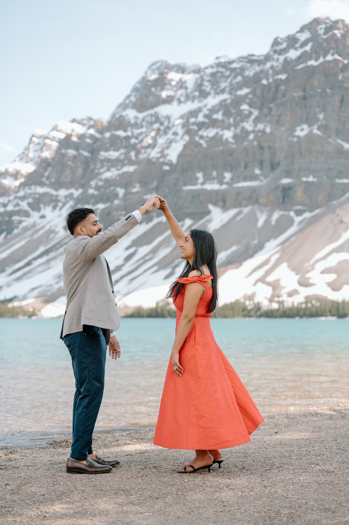 Man spinning his new fiancee around dancing by Bow Lake after proposing. 