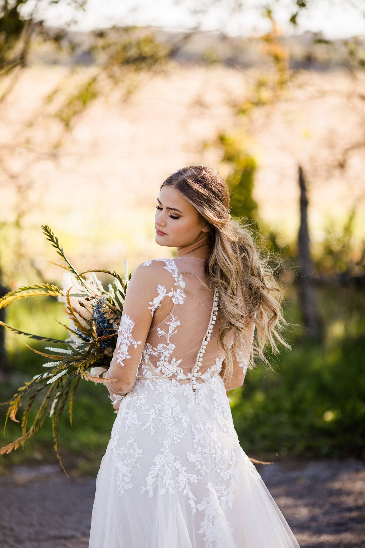 Bride in lace gown with buttons down the back looking over shoulder. 