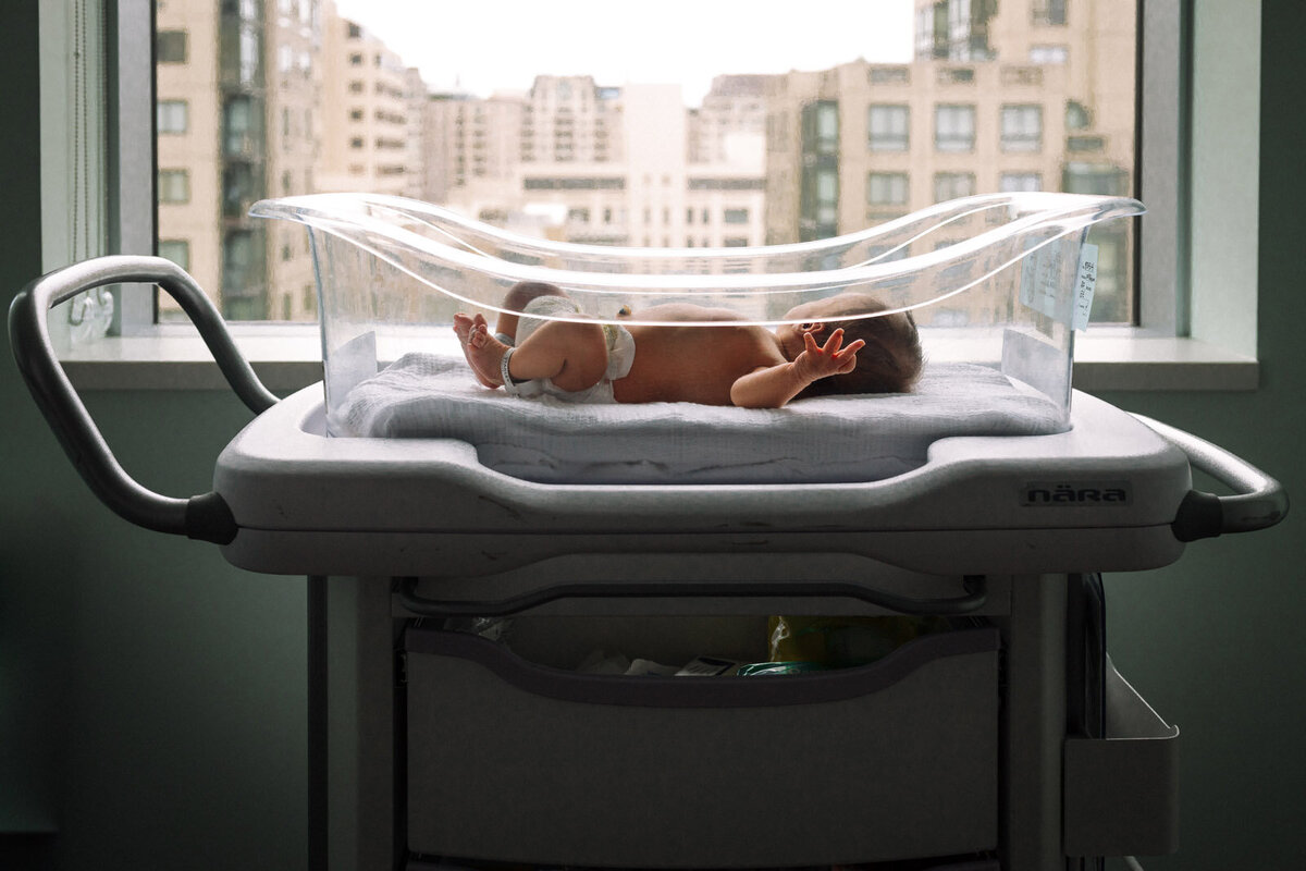 newborn in diaper laying in bassinet next to window at San Francisco hospital