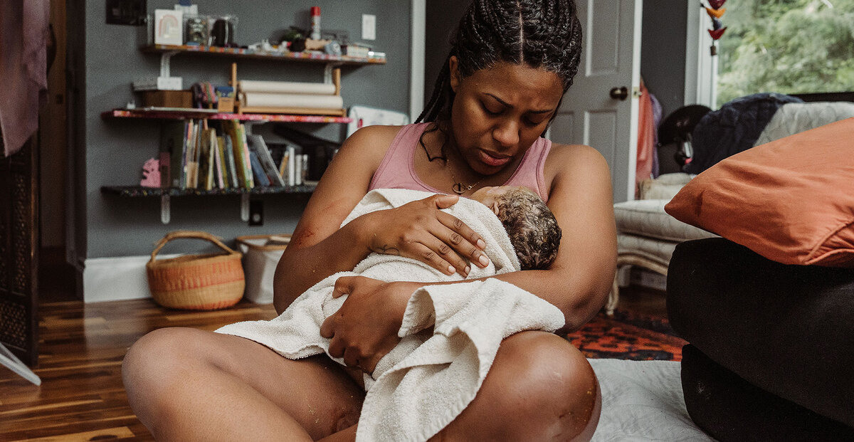 Mother holds her newborn baby in her living room at her home birth in Portland