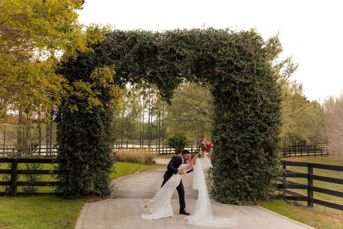 Groom Dipping bride under arch at Club Lake Plantation Apopa Florida