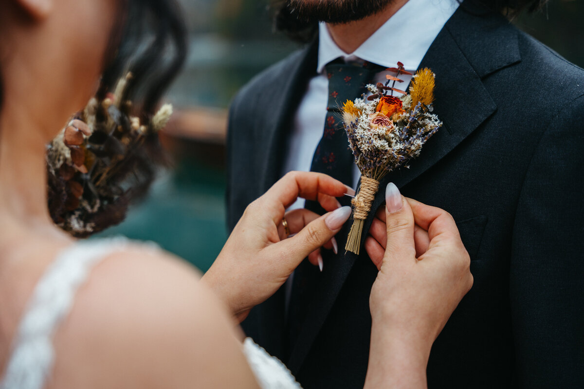 Bride fixing groom’s dried floral boutonniere during Dolomites wedding