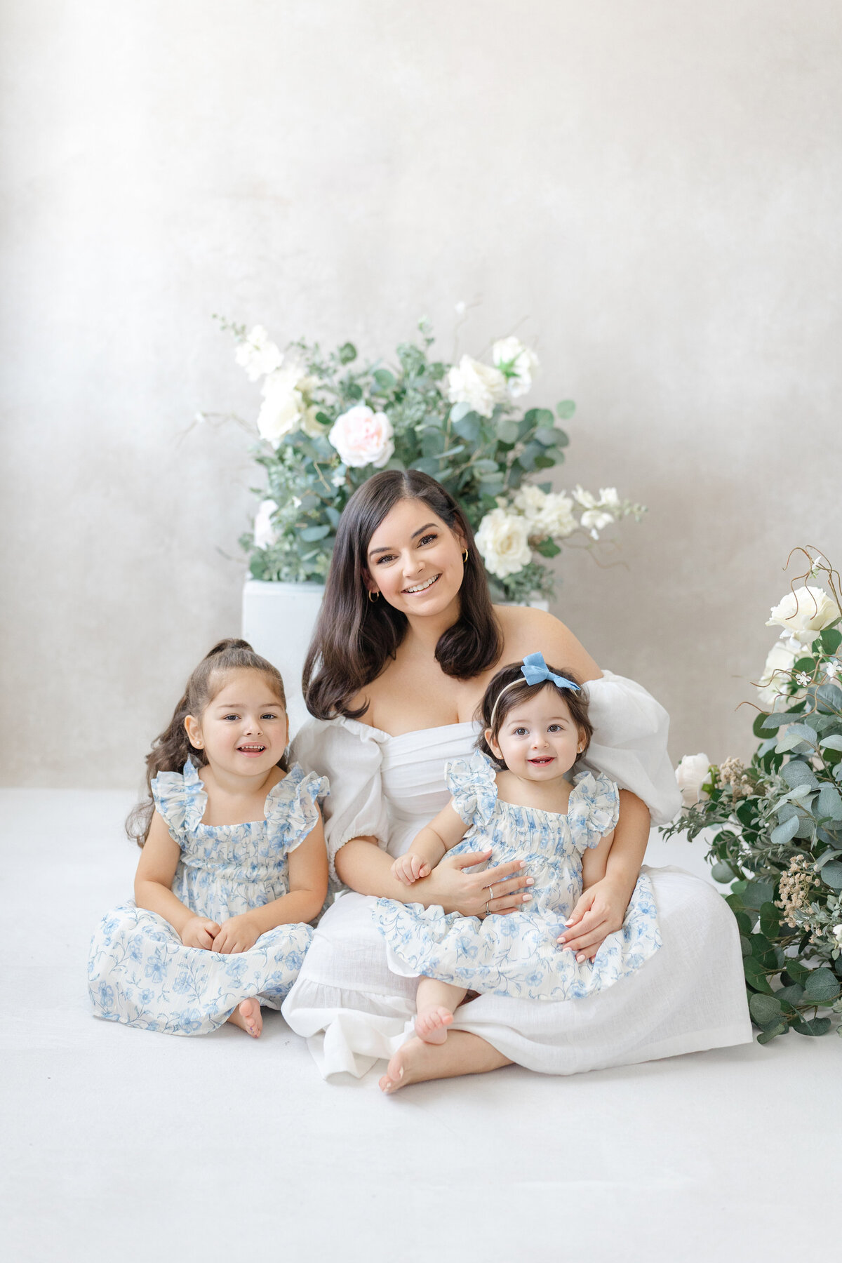 Joyful Tampa motherhood portrait of mom and two daughter smiling in soft natural light studio