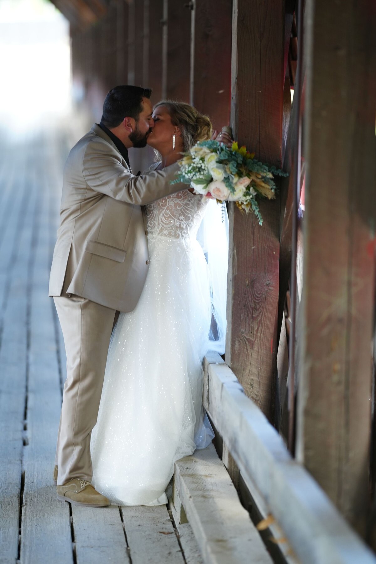 The groom shares a tender kiss with the bride, capturing a moment of pure romance and affection. This intimate gesture highlights their deep connection and love on their special day.