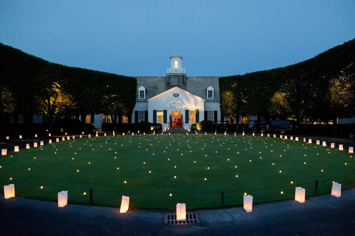 A photo of the Shoresacres Country Club at night with candles surrounding the entrance. 