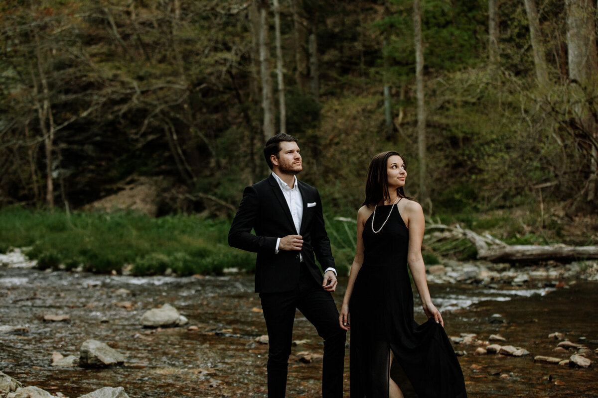 Bride and groom holding hands looking at each other while standing in front of rolling hills with the sunlight coming down on them