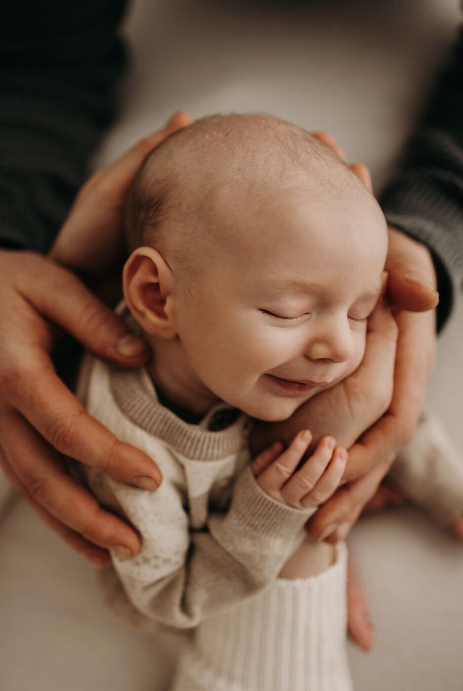 Smiling newborn baby being gently cradled in loving hands, Mullingar newborn photography
