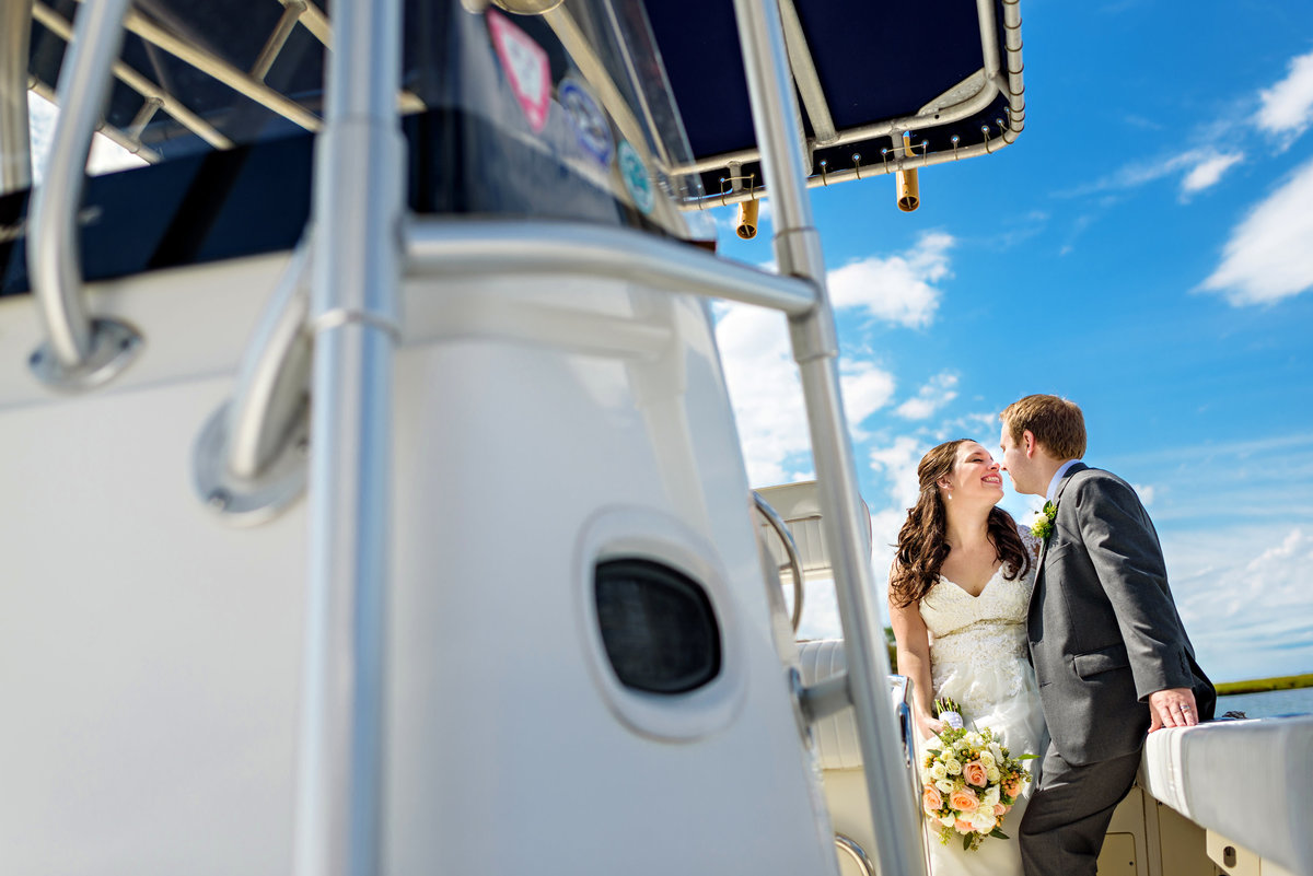 A bride leans in for a kiss from her groom on a yacht after their wedding on long beach island, NJ.
