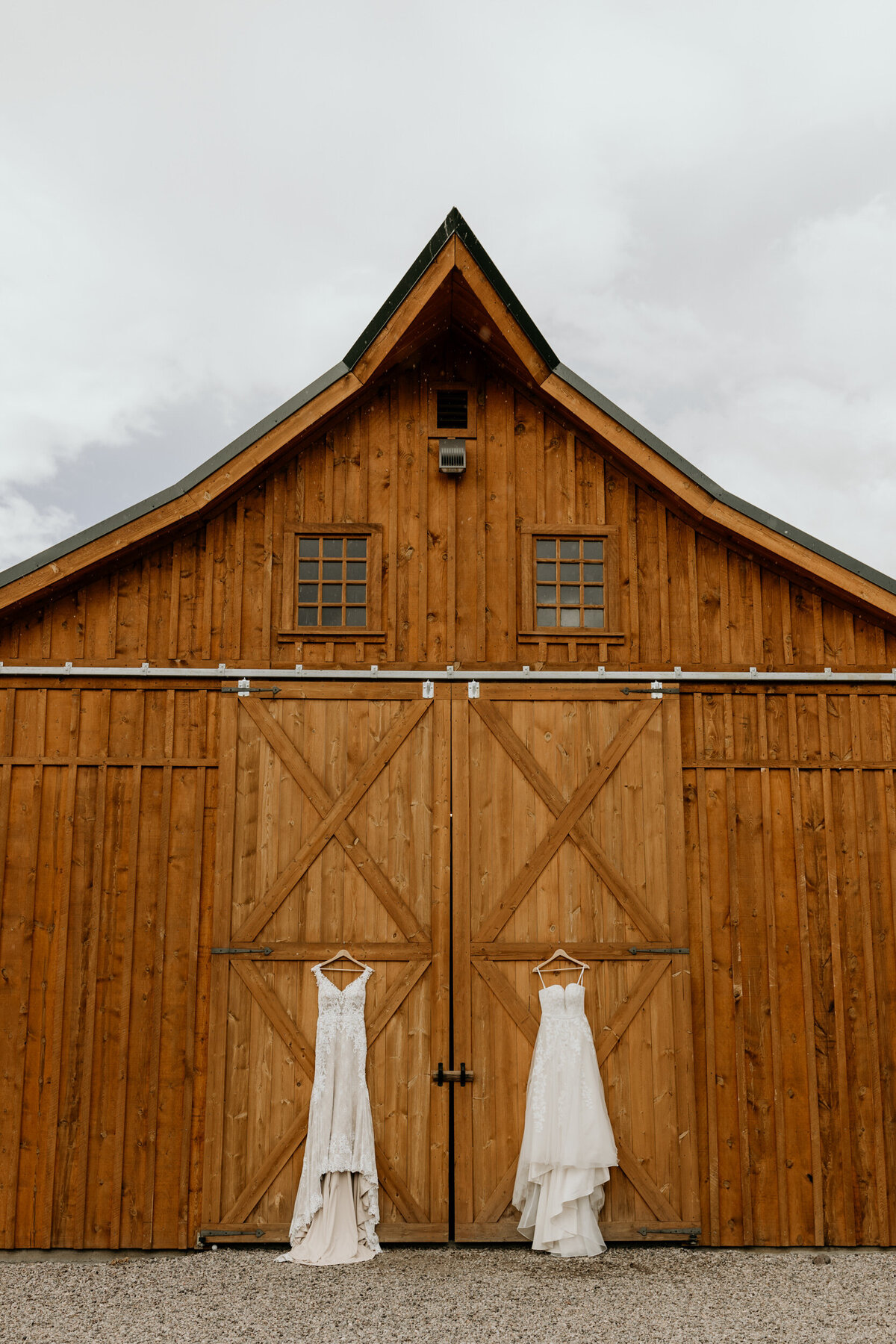 two wedding dresses hanging on a wooden barn