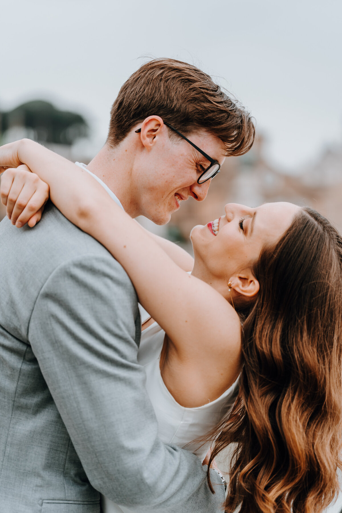 Couple smiling and holding each other on Roman bridge.