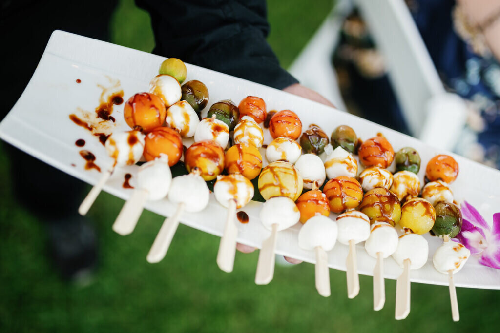 A close-up of delicious Caprese skewers with mozzarella, cherry tomatoes, and balsamic glaze, beautifully presented as a wedding appetizer. Destination wedding photography by Claudia Amalia Photography.