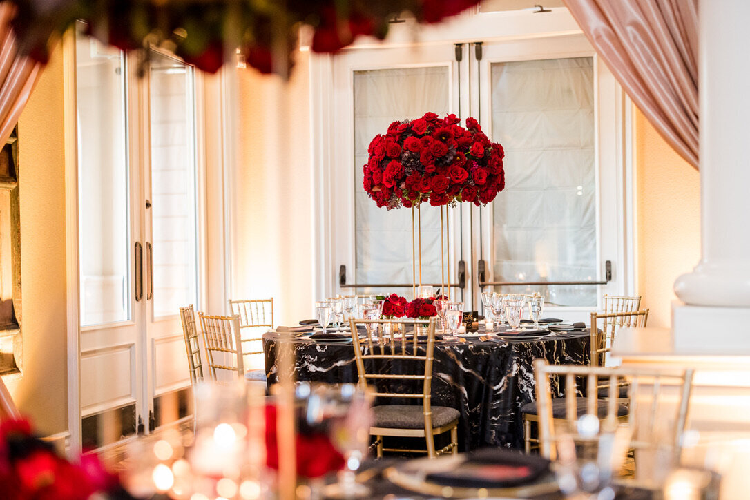Tall arrangement, red flowers, black and gold linens, gold chairs, formal wedding, elevated arrangements