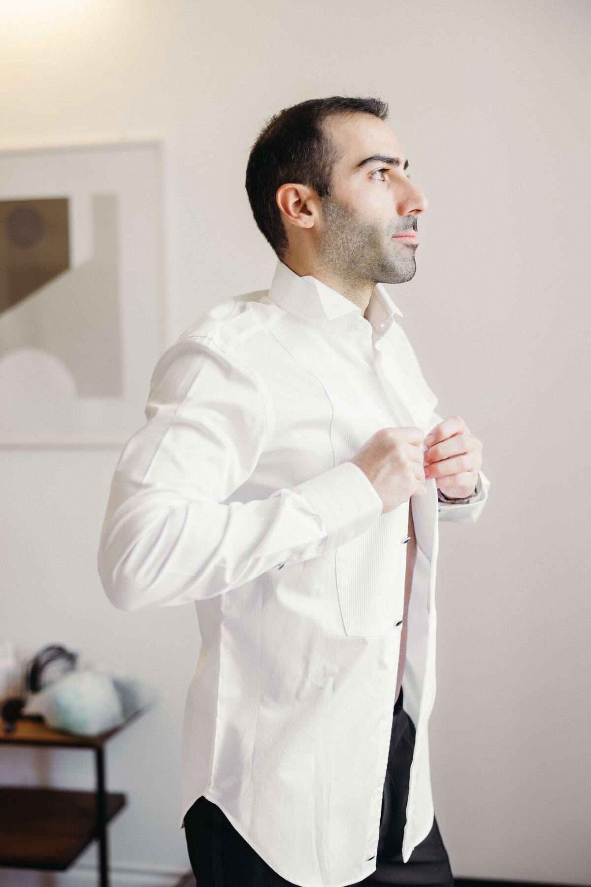 Groom adjusting shirt collar while getting ready in Rome

