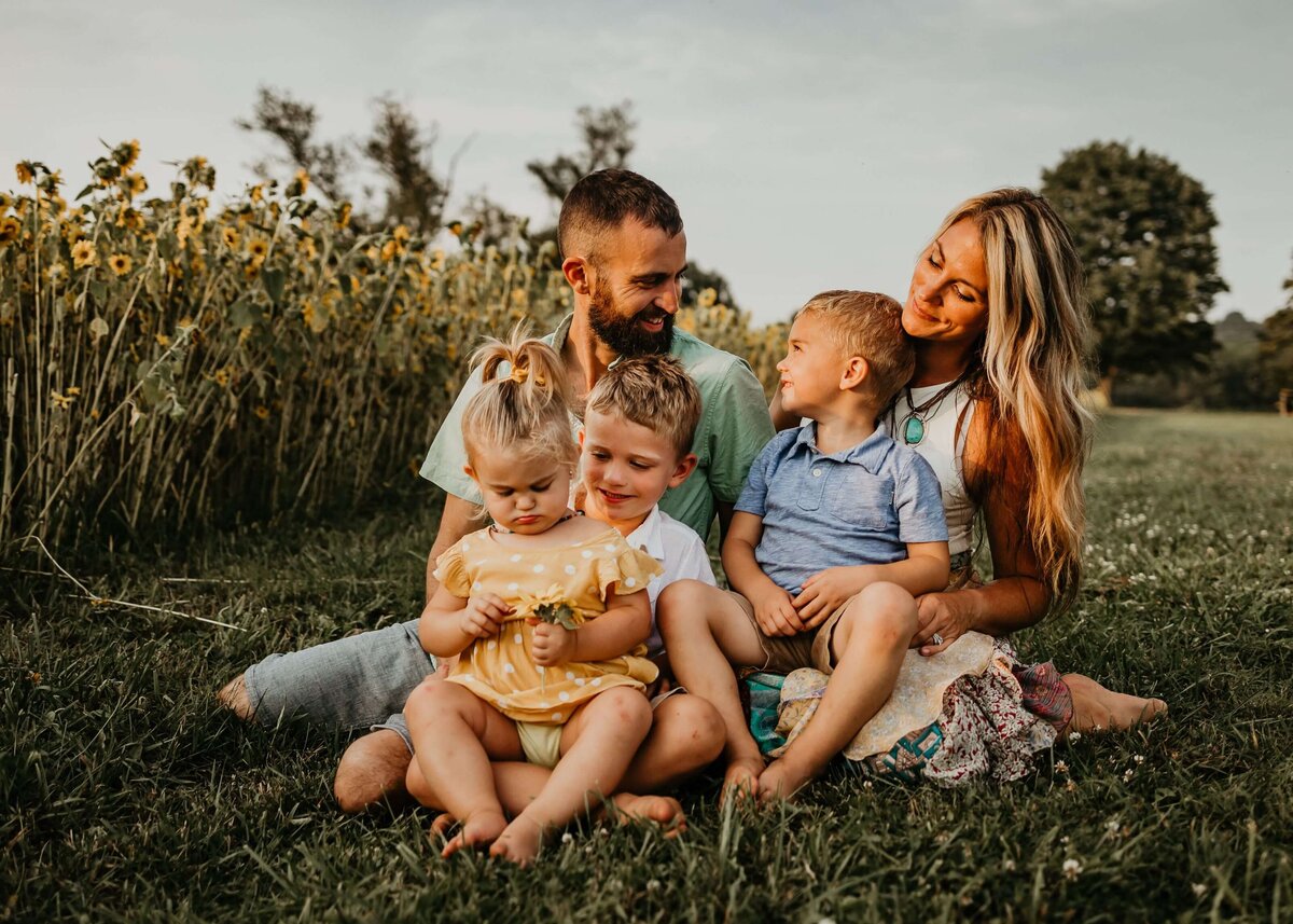 A family poses in a field with sunflowers, captured by a Pittsburgh family photographer.